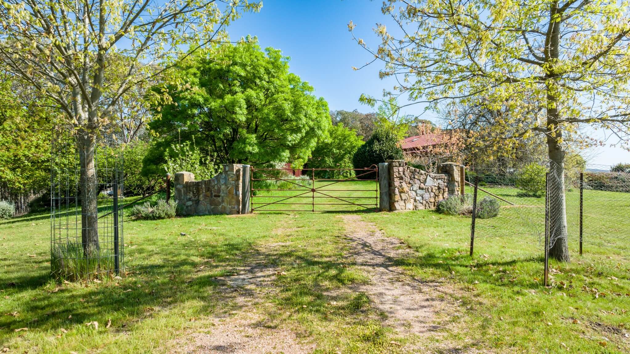 A photo of a dirt road leading to a gate entrance near the property home