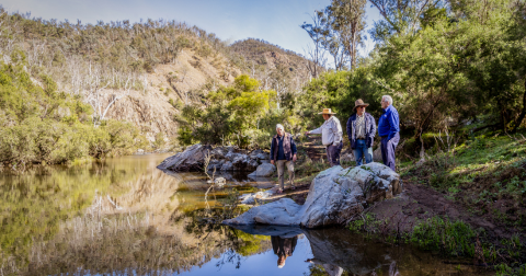 3 Wallamara landholders stand on the edge of a river with BCT worker