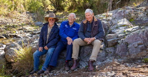 3 Wallamara landholders sit on a rock laughing