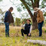 Three people squat to observe the species in a small marked out grassy area