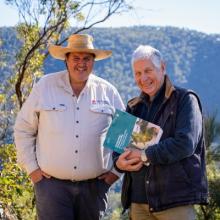 BCT staff member and landholder stand side by side holding private land conservation booklet